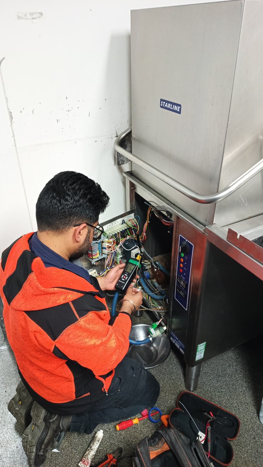 Technician working inside a Starline commercial dishwasher